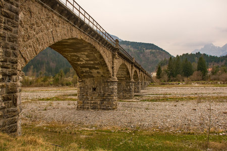 A stone bridge passing over the Torrente Degano river just north of Ovaro village in Carnia, Udine Province, Friuli-Venezia Giulia, north east Italyの写真素材