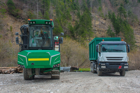 An industrial wood chipper with off-road capability and a truck on a logging site near the mountain village of Forni Avoltri in Carnia, Udine Province, Friuli-Venezia Giulia, north east Italyの写真素材