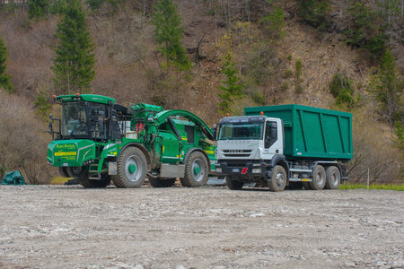Forni Avoltri, Italy - April 8th 2023. An industrial wood chipper with off-road capability and a truck on a logging site near the mountain village of Forni Avoltri in Carnia, Udine Province, Friuli-Venezia Giulia, north east Italyのeditorial素材