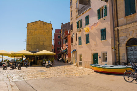 Rovinj, Croatia - July 9th 2023. Customers enjoy food and drink in the shade in the historic centre of Rovinj old town in Istria, Croatiaのeditorial素材