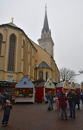 Villach, Austria - December 24th 2022. Christmas market stalls on Hauptplatz street on a slightly foggy Christmas Eve in the historic centre of Villach in Carinthia, Austria. The spire of the parish church of Saint Jacob is in the backgroundのeditorial素材