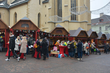 Villach, Austria - December 24th 2022. Christmas market stalls on Hauptplatz street on Christmas Eve in the historic centre of Villach in Carinthia, Austria. The parish church of Saint Jacob is in the backgroundのeditorial素材