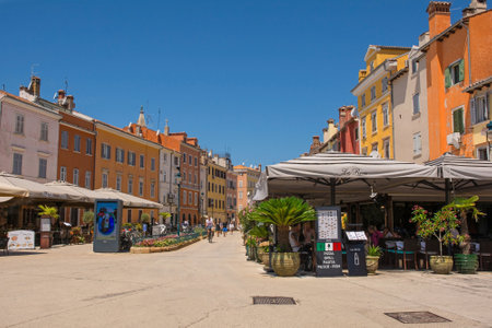 Rovinj, Croatia - July 9th 2023. Customers enjoy food and drink in the shade in the historic centre of Rovinj old town in Istria, Croatiaのeditorial素材