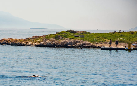 Novi Vinodolski, Croatia - September 11th 2023. Tourists who have swum out to the island of San Marino off the Adriatic coast of Novi Vinodolski, Primorje-Gorski Kotar Countyのeditorial素材