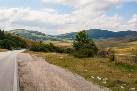 Gornje Ratkovo, Bosnia - September 5th 2023. Trash litters the roadside in the summer landscape near Gornje Ratkovo in the Ribnik municipality of Banja Luka region, Republika Srpska, Bosnia and Herzegovina. Early Septemberのeditorial素材