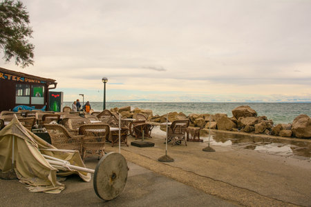 Piran, Slovenia - September 17th 2022. Restaurants are closed for the day and their umbrellas safely laid down as rough waves and high water hit the waterfront of Piran town in Slovenia in mid Septemberのeditorial素材