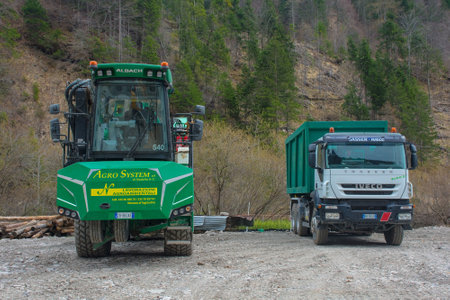 Forni Avoltri, Italy - April 8th 2023. An industrial wood chipper with off-road capability and a truck on a logging site near the mountain village of Forni Avoltri in Carnia, Udine Province, Friuli-Venezia Giulia, north east Italyのeditorial素材