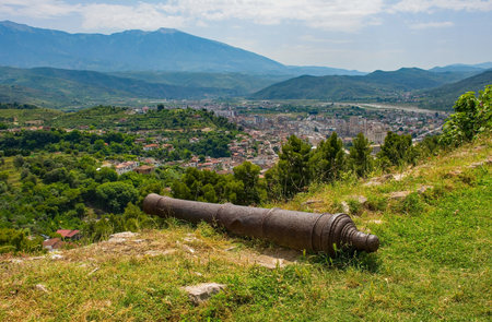 A view of the landscape around the southern Albanian town of Berat in June. Taken from Berat Castle with foreground cannon barrel, and showing the Lagja 30 Vjetori district in the background. A rural landscape of olive groves, pine trees and terraced fieldsの写真素材