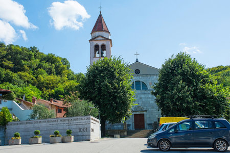 The 18th century baroque-style Parish Church of St Stephen in Solkan, Nova Gorica, Slovenia. The text in Latin, Slovenia and Italian on the foreground wall commemorates the founding of Solkan in 1001. The church is called Zupnijska Cerkev Sv. Stefana in Slovenianの写真素材