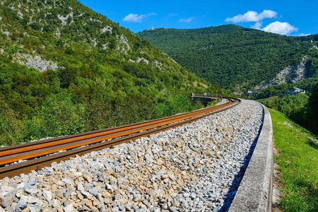 The rail line crossing the Solkan Bridge over the Soca River at Solkan near Nova Gorica , Primorska, Slovenia. It is the longest stone arch railroad bridge in the world, and second longest stone arch bridge. Part of the Soca Valley karst landscape. Mount Sabotin on the leftの写真素材