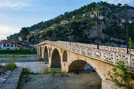 Gorica Bridge in Berat, Albania, a UNESCO World Heritage Site. This Ottoman footbridge across the River Osum links the Gorica and Mangalem historic quarters, and is an iconic landmark of Berat. Kalaja Hill and Berat castle are in the background. Made of local stone with seven semi-circular arches. Originally wooden in the 18th century, it was rebuilt in stone in the early 19th century. Viewed from the Gorica side of the river in the low sun of the late afternoon. Ura e Gorices in Albanianの写真素材