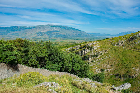 The rugged landscape in the Drino Valley area just outside Gjirokaster, central Albania. An old stone wall near the foreground separates different areas of land. A popular area for walking and hiking for locals and tourists alike. June, early summerの写真素材
