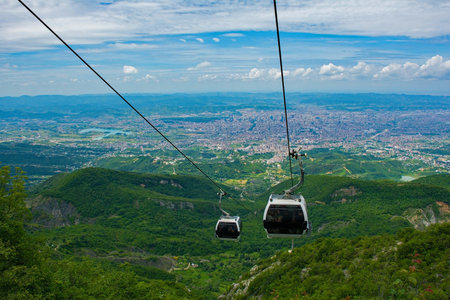 Cable cars ascend Mount Dajti, offering breathtaking panoramic views of the sprawling urban landscape below and the surrounding green countrysideの写真素材