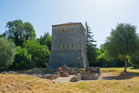 The 15th century Venetian Tower in Butrint Archaeological Park, within Butrint National Park, southern Albania. A UNESCO World Heritage Site. Also called Kulla Venciane, it guarded the Vivari Channel along with the triangular fortress. A Roman public bathhouse features characteristic bathing rooms with remnants of a hypocaust system is in front of the towerの写真素材