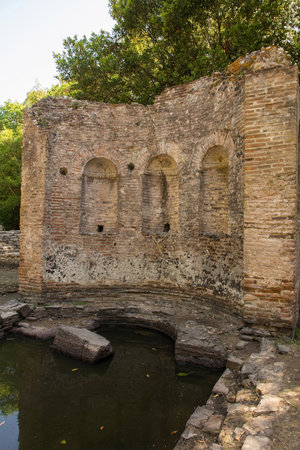 A nymphaeum fountain characterised by three niches in the 2nd century Gymnasium Complex in Butrint Archaeological Park, within Butrint National Park, southern Albania. A UNESCO World Heritage Site. Also called the Palaestra, it was likely a place for athletic training and social gatherings. It has a rectangular courtyard surrounded by porticos, typical of urban Roman gymnasiumsの写真素材