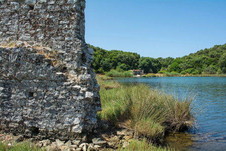 Late-antique and medieval walls on the shore of Lake Butrint in Butrint Archaeological Park, within Butrint National Park, southern Albania. A UNESCO World Heritage Site. Constructed during 5th-6th centuries and known as the Western Defences, they consist of rectangular worked limestone bonded with grey & white mortarの写真素材
