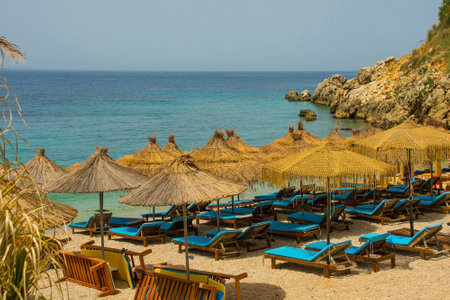 A resort on Prinos Beach at the southern end of Himare Bay on the coast of south Albania, part of the Albanian Riviera. A morning in June, early summer, before the sun worshippers have arrived. Located in Vlore County, Himare lies between the Ceraunian Mountains and the Ionian Sea and is a major tourism centreの写真素材