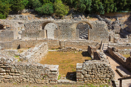 Ruins in the Roman Forum in Butrint Archaeological Park, within Butrint National Park, southern Albania. A UNESCO World Heritage Site. The amphitheatre is in the centre behind the arched entrances. This was Butrint's civic centre, surrounded by administrative and commercial buildings, and including a marketplace, temples and a basilicaの写真素材