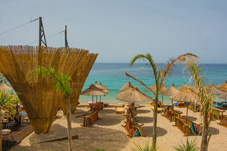 A resort on Prinos Beach at the southern end of Himare Bay on the coast of south Albania, part of the Albanian Riviera. A morning in June, early summer, before the sun worshippers have arrived. Located in Vlore County, Himare lies between the Ceraunian Mountains and the Ionian Sea and is a major tourism centreの写真素材