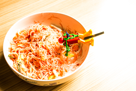 Fried noodle pink in a bowl and small robots on a spoon at home.の写真素材