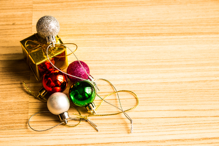 Color balls and gift box christmas left side on a wooden brown floor background.の写真素材