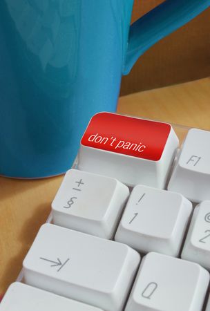 a computer keyboard with the instructions don't panic with a mug in the backgroundの写真素材