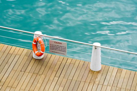 Warning sign and life saver on a railing along a coastal pathの写真素材
