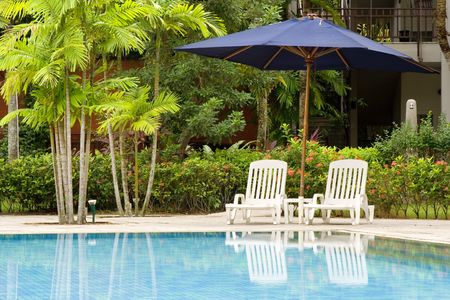 Swimming pool with empty deck chairs at its edgeの写真素材