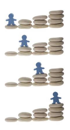 Series of figurine on different stacks of pebbles isolated on white backgroundの写真素材