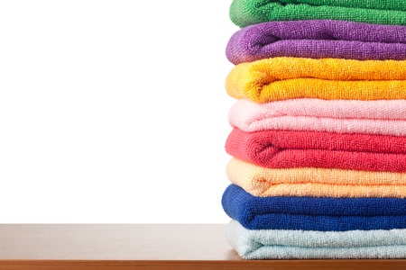 Stack of colorful microfiber towels on a table against white backgroundの写真素材