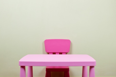 Pink color children desk and chair against a blank wallの写真素材