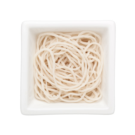 Uncooked noodles in a square bowl isolated on white backgroundの写真素材