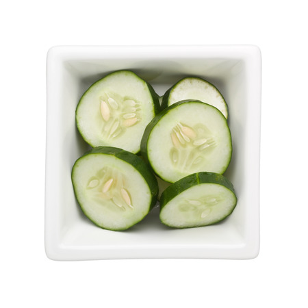 Sliced cucumber in a square bowl isolated on white backgroundの写真素材
