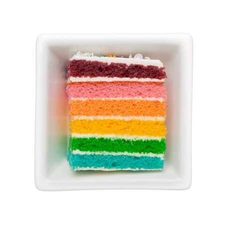 Slice of rainbow cake in a square bowl isolated on white backgroundの写真素材