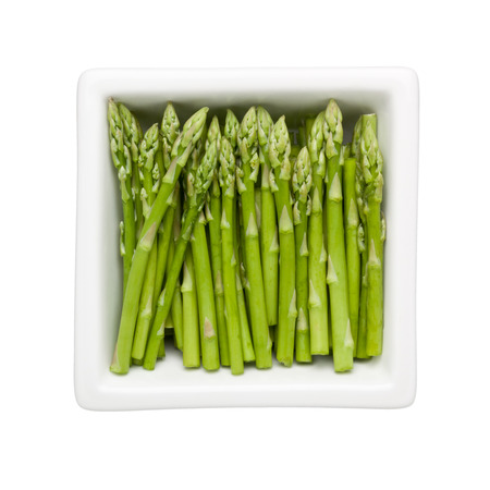 Pieces of asparagus in a square bowl isolated on white background;の写真素材