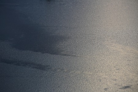 Water surface frozen to a rippled structure, sunlight reflections on the right.