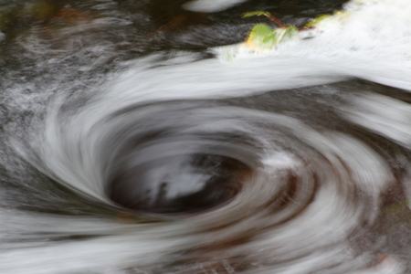Blurred vortex in water with spray and a birch twig.の写真素材
