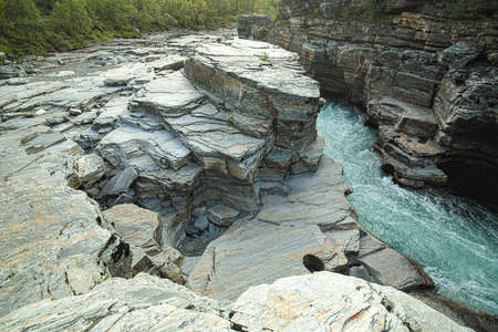 Rapids of the swedish stream Abiskojakka in slate river bed.