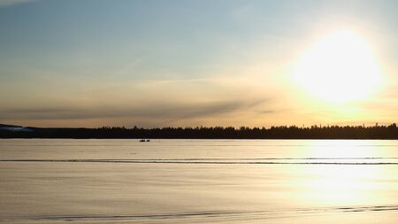 Silhouettes of group of people with snowscooter on frozen solid lake Norsjon in Vasterbotten, Sweden.の写真素材