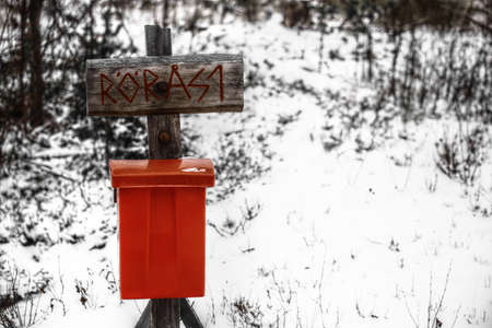 Archaic street sign with a red mailbox in snow.の写真素材