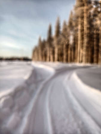 Blurred image of snowmobile tracks next to a forest.の写真素材