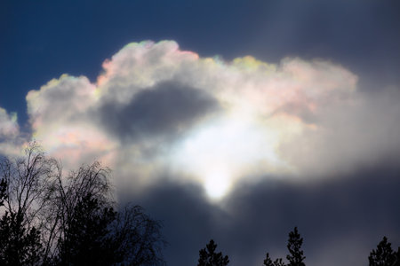 Sun behind rainbow colored clouds in April.の写真素材