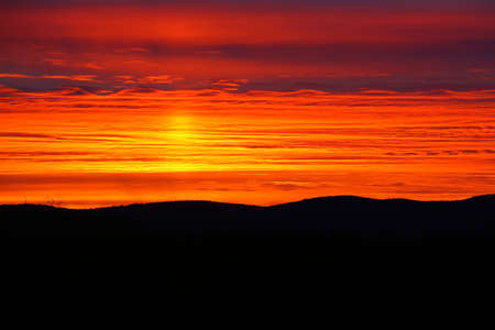 Layered cloudscape and dusk over mountain forest silhouette.の写真素材