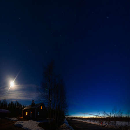Moon and dusk at midnight over house in Swedish Lapland.の写真素材