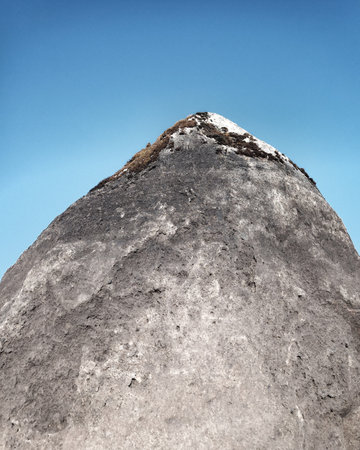 Mossy rock resembling a mountain and blue sky.の写真素材