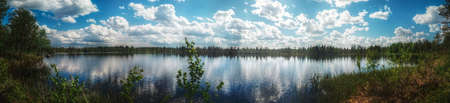 Panorama of small Swedish lake with heavy clouds and sunlight.の写真素材
