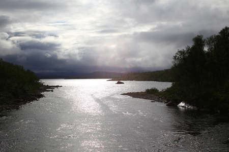Dark backlit shot of lake at Vadvetjakka National Park in Sweden.の写真素材