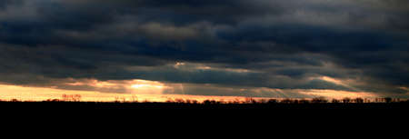 Sunbeams breaking through cloud cover in backlit panorama shot.の写真素材
