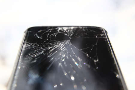 Macro of phone with broken display with white background.