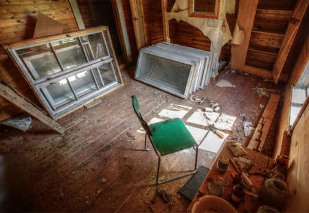 Ruined interior of an old wooden house with chair and used windows.の写真素材